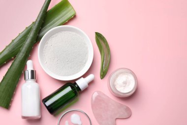 Kozmetik ürünlerle düz kompozisyon ve pembe arka planda aloe yaprakları. Metin için boşluk