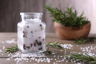 Cam kavanozda biberli tuz ve ahşap masada biberiye.