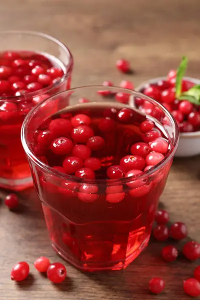 Tasty cranberry juice in glasses and fresh berries on wooden table, closeup