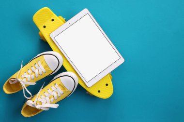 Modern tablet, kaykay ve açık mavi arka planda ayakkabılar. Metin için boşluk