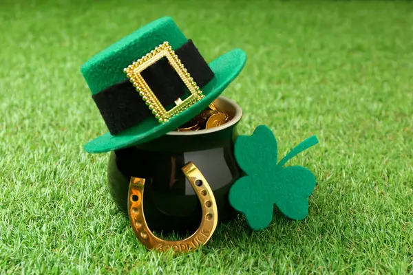 Aziz Patrick Günü. Leprikon şapkalı, at nalı ve yeşil çimlerde süslü yonca yaprağı olan bir tencere altın.