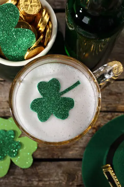 St. Patrick\'s day party. Green beer, leprechaun hat, pot of gold and decorative clover leaves on wooden table, flat lay