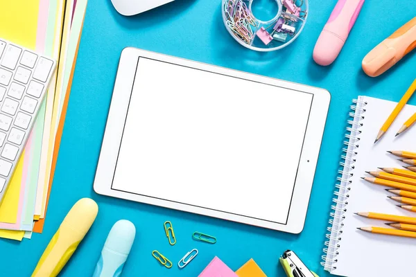 Açık mavi zemin üzerine modern tablet ve kırtasiye malzemesi, düz. Metin için boşluk