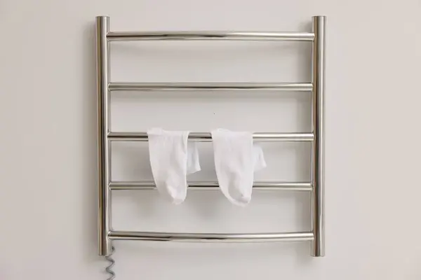 Heated towel rail with socks on white wall