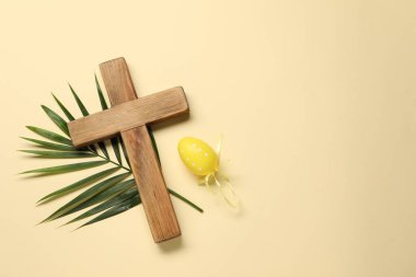 Ahşap haç, Paskalya yumurtası ve bej arka planda palmiye yaprağı, üst manzara. Metin için boşluk