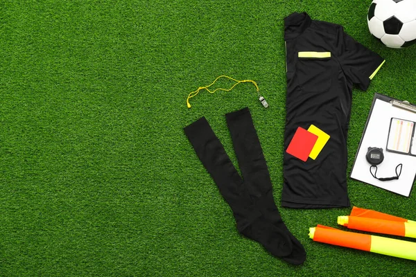 Üniforma, futbol topu ve yeşil çimlerde diğer hakem ekipmanları, düz konum. Metin için boşluk