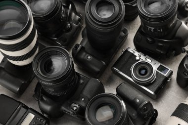 Gri masadaki modern kameralar, yakın plan. Profesyonel fotoğraf ekipmanları
