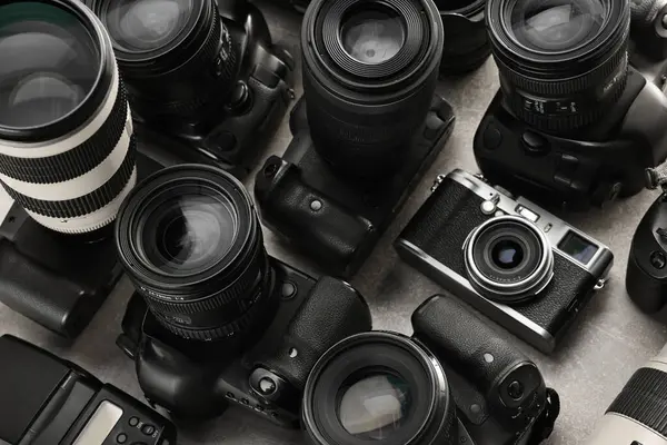 Gri masadaki modern kameralar, yakın plan. Profesyonel fotoğraf ekipmanları