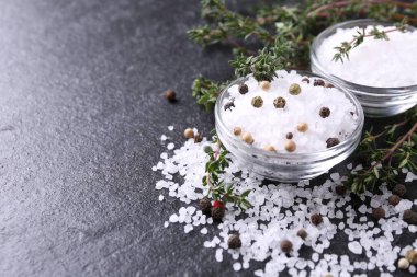 Taze kekikli tuz ve koyu gri desenli masada biber, yakın plan. Metin için boşluk