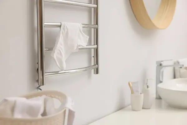 Heated towel rail with underwear on white wall in bathroom