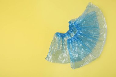 Sarı arka planda bir çift mavi tıbbi ayakkabı kılıfı, üst manzara. Metin için boşluk