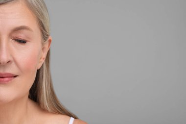 Gri arka planda sağlıklı cildi olan güzel, olgun bir kadın. Yakın plan. Metin için boşluk