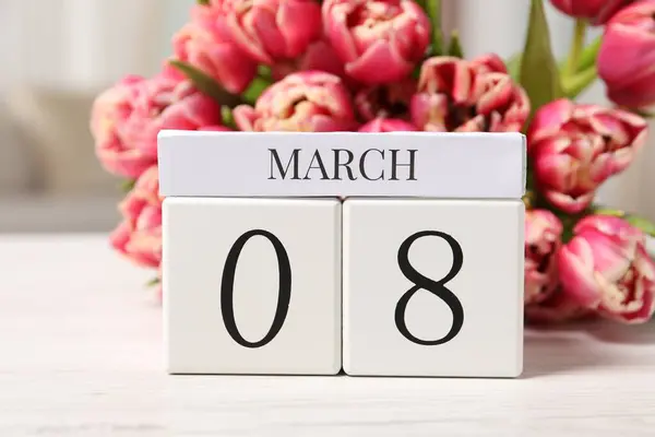 International Women\'s day - 8th of March. Block calendar and bouquet of beautiful tulips on white wooden table, closeup