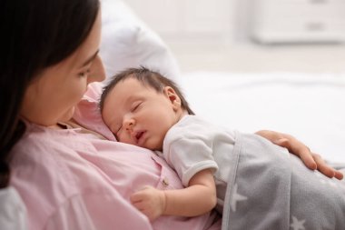 Anne, uyuyan yeni doğmuş bebeğiyle evde yatıyor.