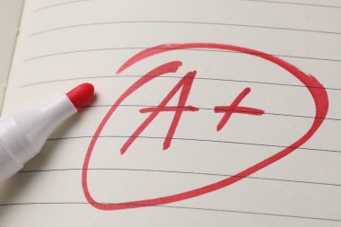 Okul derecesi. Kırmızı harf A. Not defteri kağıdında artı işareti var. Yakın plan.