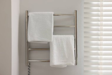 Heated rail with towels on white wall in bathroom clipart