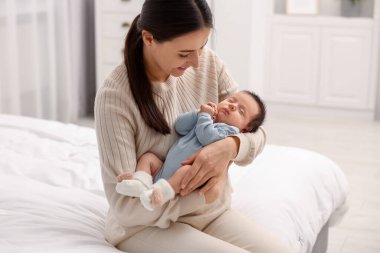 Anne, uyuyan yeni doğmuş bebeğiyle evde yatıyor.