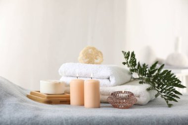 Spa kompozisyonu. Yumuşak gri yüzeyde yanan mumlar, sabunlar, havlular ve lifler.