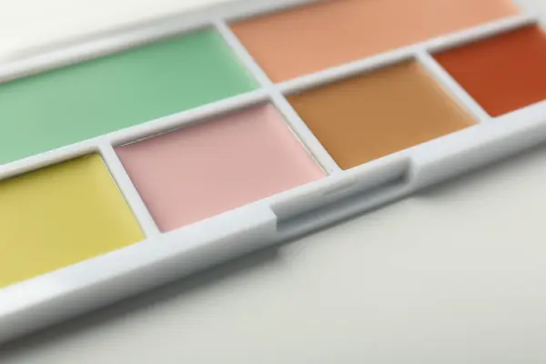 Colorful correcting concealer palette on white background, closeup