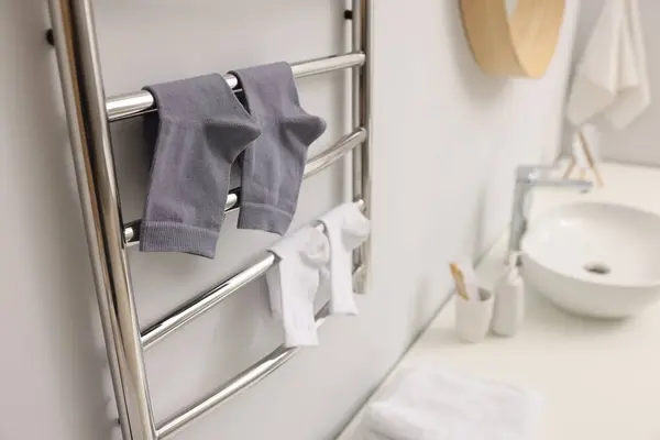 Heated towel rail with socks on white wall in bathroom