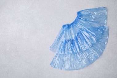 Açık gri arka planda bir çift mavi tıbbi ayakkabı kılıfı, üst manzara. Metin için boşluk