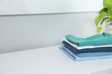 Sıralama ve düzenleme. Beyaz masa içerisindeki katlanmış kıyafetlerin yığını, metin için boşluk