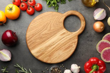 Tahta kesme tahtasıyla düz kompozisyon ve koyu dokulu masa üzerinde ürünler.