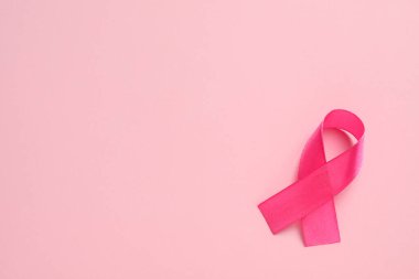 Renk arkaplanı üzerine pembe kurdele, metin için üst görünüm ve boşluk. Göğüs kanseri farkındalığı
