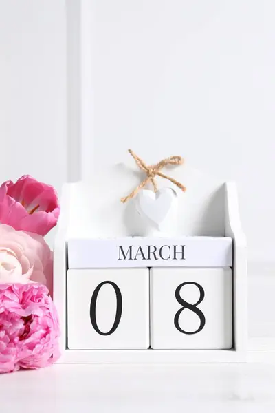 International Women's day - 8th of March. Wooden block calendar and beautiful flowers on white table