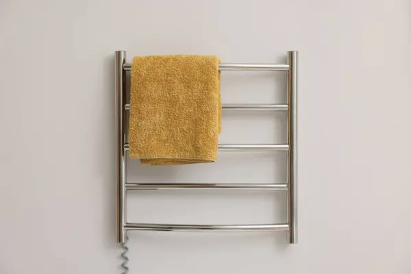 Heated rail with yellow towel on white wall