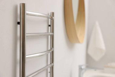 Banyoda beyaz duvarda ısıtmalı havlu parmaklığı, yakın plan.