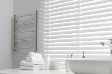 Banyodaki beyaz duvarda ısıtılmış havlu parmaklığı.