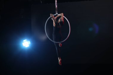 Genç bir kadın, arka planda hava halkası üzerinde akrobatik hareketler yapıyor.