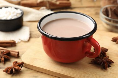 Bardakta lezzetli sıcak çikolata ve ahşap masada baharatlar, yakın plan.