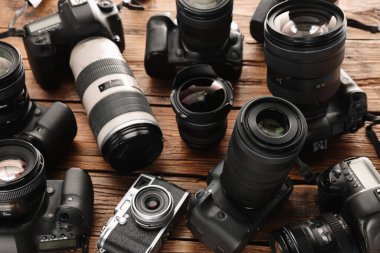 Ahşap masada modern kameralar, yakın plan. Profesyonel fotoğraf ekipmanları
