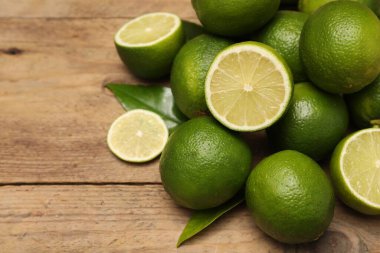 Tahta masanın üzerinde taze limon ve yapraklar yığını, yakın plan. Metin için boşluk