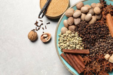 Farklı baharatlar ve fındıklar açık gri desenli masada, düz yerde. Metin için boşluk