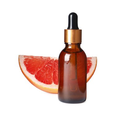 Bir şişe greyfurt yağı ve beyaz üzerine izole edilmiş taze meyve.