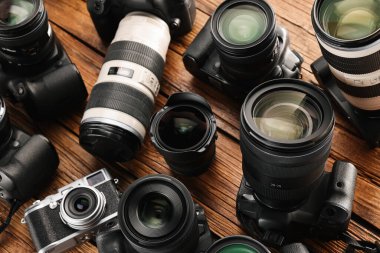 Ahşap masada modern kameralar, yakın plan. Profesyonel fotoğraf ekipmanları