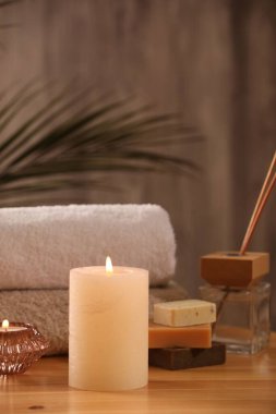 Spa kompozisyonu. Yanan mumlar, havlular, sabun ve kamış oda spreyi ahşap masada, yakın plan.
