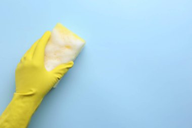 Açık mavi arka planda köpüklü kauçuk eldivenli sünger, üst manzara. Metin için boşluk