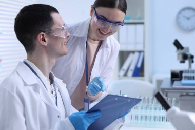 İçerideki masada laboratuvar test formlarıyla çalışan bilim adamları.