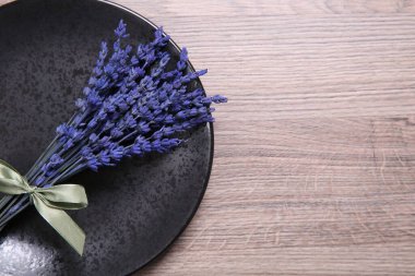 Çok güzel korunmuş lavanta çiçekleri ve ahşap masa üzerinde bir tabak, üst manzara. Metin için boşluk