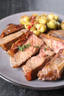 Lezzetli kızarmış et, sebze ve kekik siyah masada, yakın plan.