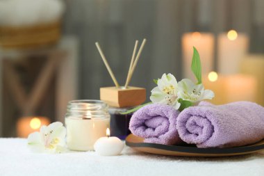 Bulanık arka planda beyaz havluyla farklı spa ürünleri ve çiçeklerle güzel bir kompozisyon