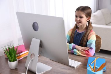 E-öğrenme. İçerideki masada çevrimiçi ders sırasında bilgisayar kullanan sevimli kız.