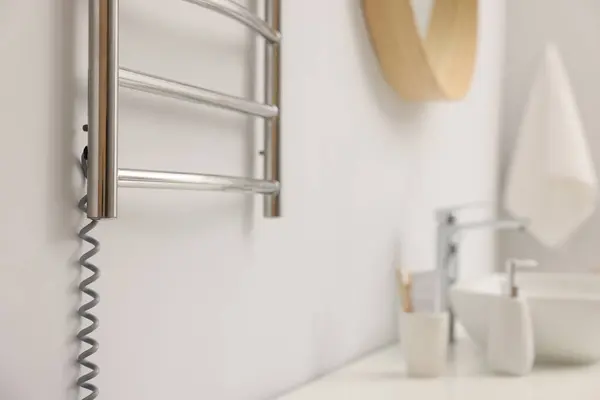 Heated towel rail on white wall in bathroom, closeup