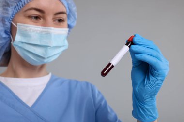 Laboratuvar testi. Açık gri arkaplanda tüpte kan örneği olan bir doktor.