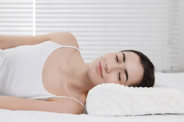 Woman sleeping on orthopedic pillow at home
