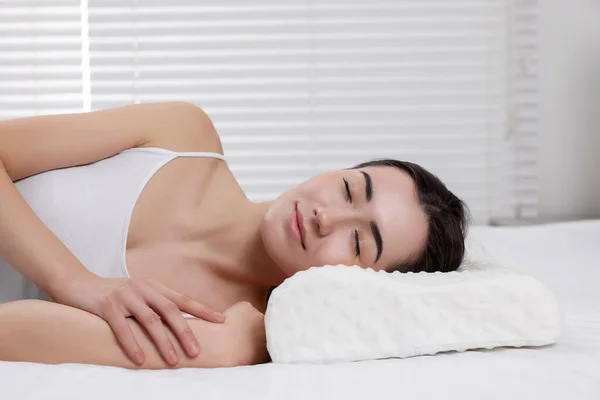 Woman sleeping on orthopedic pillow at home